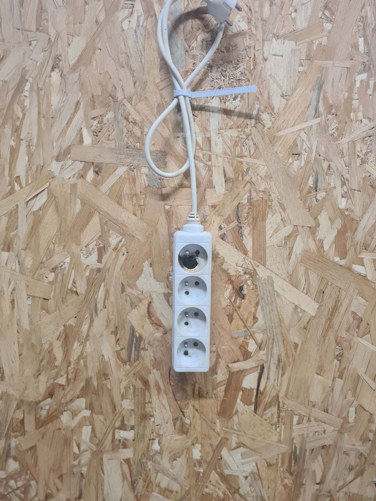 Multiprise électrique endommagée avec trace de brûlure sur une prise