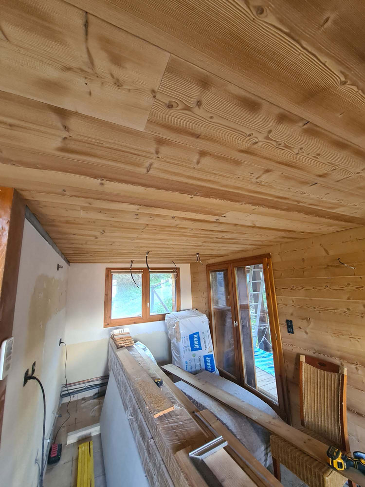 Plafond en lambris bois en cours de pose dans un chalet en rénovation, isolation Knauf visible