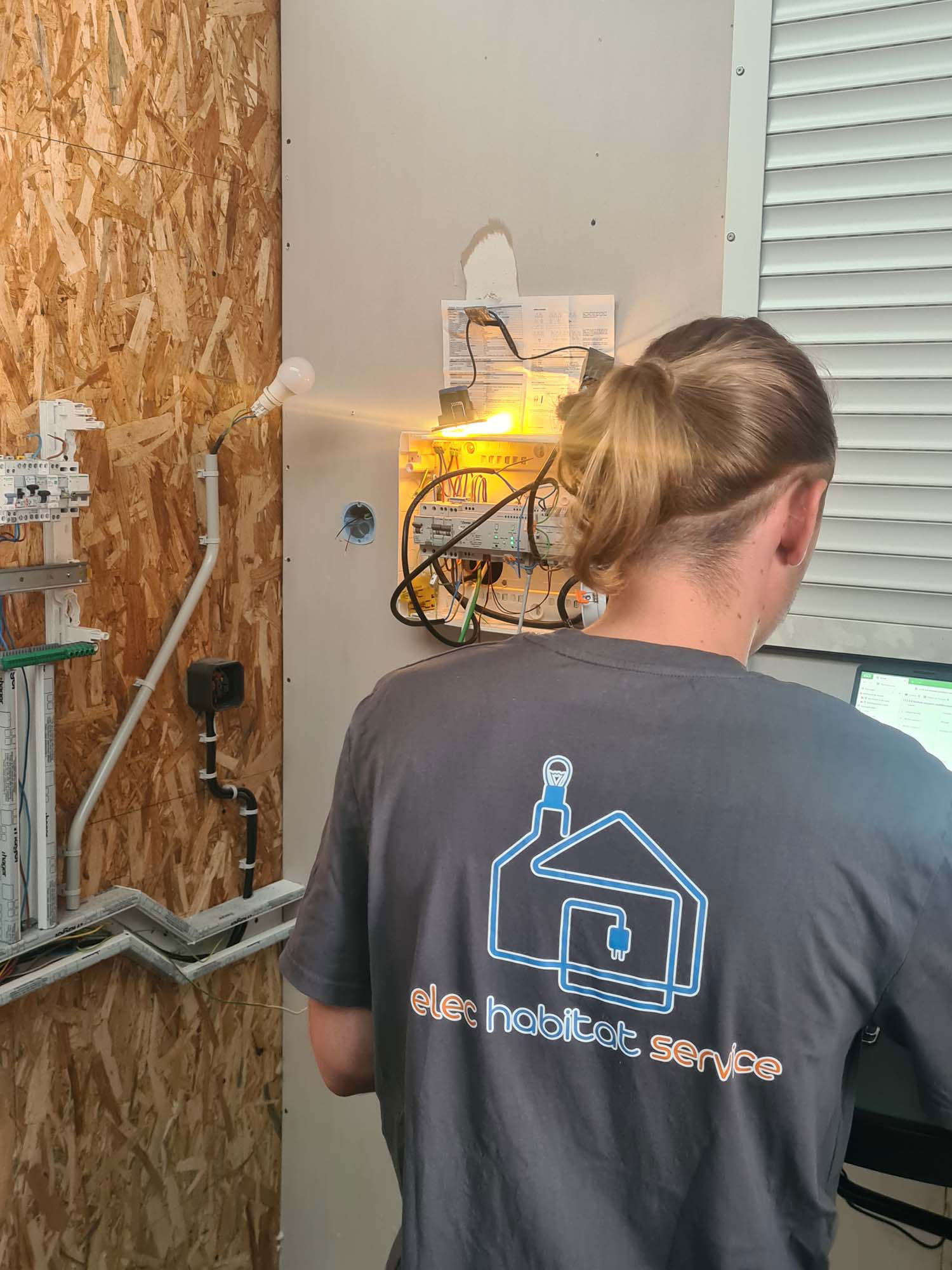 : Technicien Elec Habitat Service intervenant sur un tableau électrique en cours de chantier